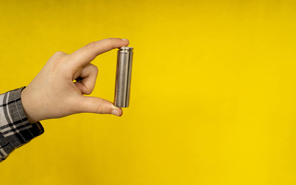 battery in hand close up on a yellow background - Zdjęcie, obraz