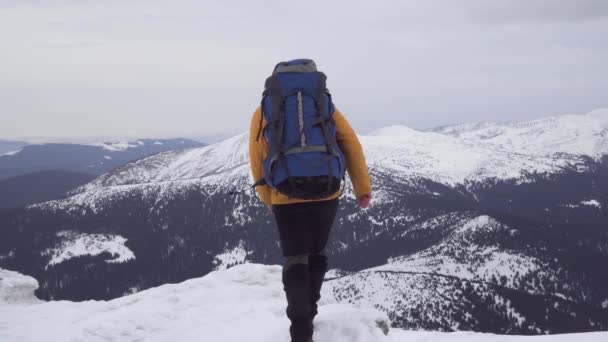 Sırt çantalı bir adam kışın dağlarda seyahat eder. - Video, Çekim