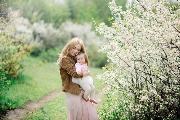 Young mother and baby in spring blooming garden - Foto, Imagem