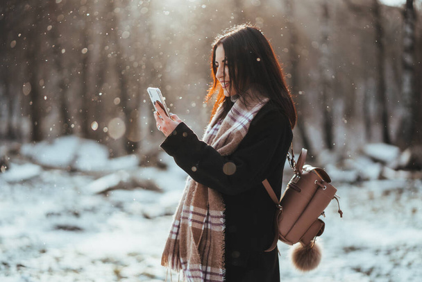 Woman talking on mobile phone. Smiling girl talking on mobile phone in cold winter day. - Foto, imagen