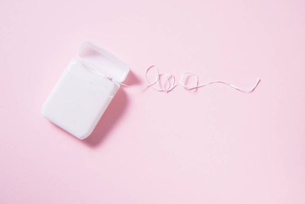 Dental floss in white plastic box on pink background - Φωτογραφία, εικόνα