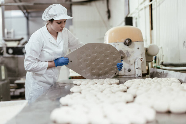 Young female worker working in large bakery. Bread preparation. - Photo, Image