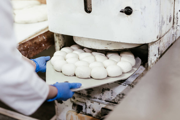 Mladá pracovnice pracující ve velké pekárně. Příprava chleba. - Fotografie, Obrázek