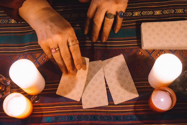 žena držící tarotovou kartu tváří dolů s tarotovým bludištěm a svíčkami kolem sebe. Koncept okultismu - Fotografie, Obrázek
