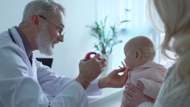 Experienced pediatrician showing toy to baby, regular health check-up, medicine - Filmagem, Vídeo