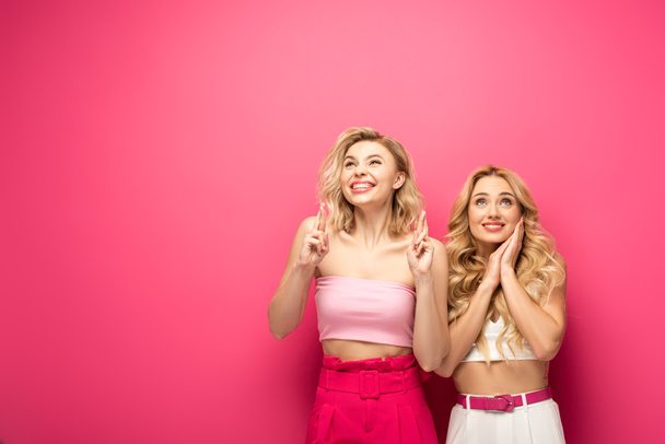 Fröhliche blonde Freunde, die auf rosa Hintergrund nach oben schauen - Foto, Bild