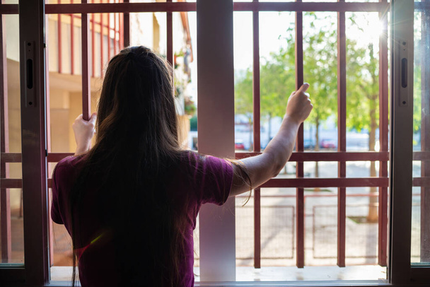 γυναίκα που γέρνει έξω από ένα παράθυρο κατά τη διάρκεια της απομόνωσης - Φωτογραφία, εικόνα