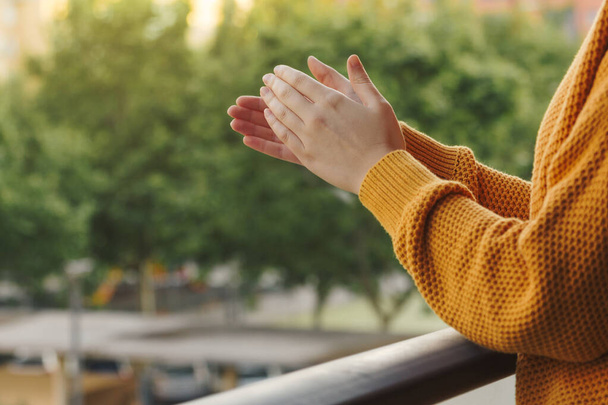 Stock photo of the hands of a young woman clapping from the balcony to support the medical team - Zdjęcie, obraz