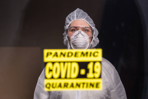 Mulher de macacão branco protetor, máscara e óculos em seu rosto. Conceito de coronavírus, pandemia, covid-19, gripe e quarentena
. - Foto, Imagem