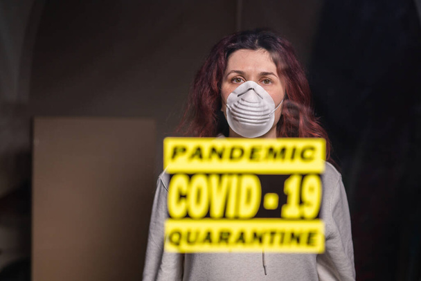 Coronavirus, quarantine, covid-19 and pandemic concept. Sad and sick woman of corona virus looking through the window. Stay at home. - Photo, Image