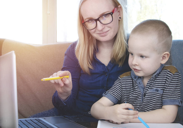 Mom and son do their homework, study online on the Internet. The concept of preschool education, home schooling of quarantined children during the coronovirus pandemic, covid-19 - Photo, Image