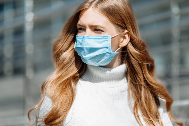 Beautiful young girl in a mask from coronovirus, student on the background of educational envy, women returning from work, remote work, covid-19 - Фото, зображення