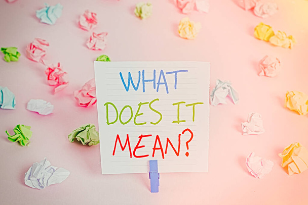 Conceptual hand writing showing What Does It Mean question. Business photo showcasing intended to communicate unclear statement Colored crumpled papers empty reminder pink floor clothespin. - Photo, Image