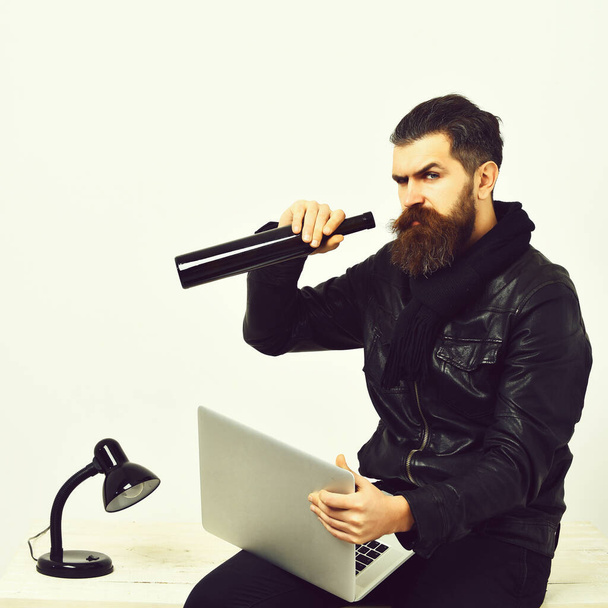 Bearded brutal caucasian hipster sitting on table with laptop - Foto, Bild