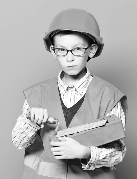 young cute builder boy on blue studio background - Foto, afbeelding