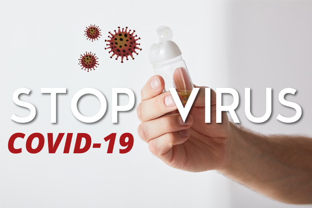 oříznutý pohled na člověka držícího dezinfekci rukou na šedém pozadí, zastavit ilustraci viru - Fotografie, Obrázek