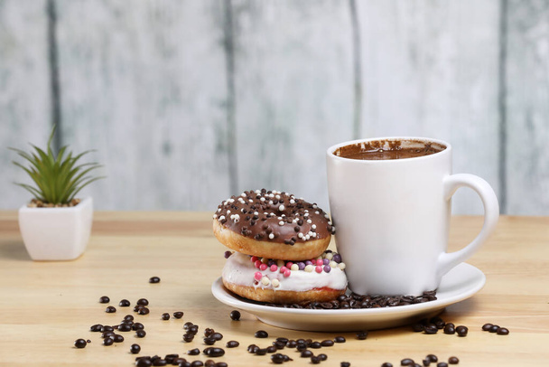 White coffee cup on a wooden table with chocolate and white chocolate donuts . Morning espresso. Morning cappuccino mug.  - Photo, Image