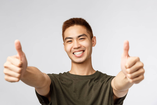 People, different expressions and lifestyle concept. Close-up portrait of enthusiastic japanese guy saying yes, approve product, give recommendation and guarantee best quality, thumbs-up - Foto, immagini