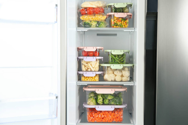 Containers with different frozen vegetables in refrigerator - Foto, afbeelding