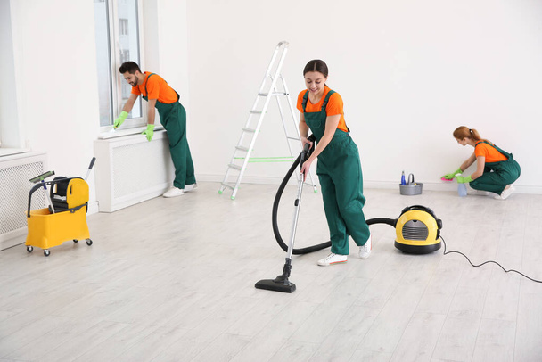 Team of professional janitors in uniforms cleaning room - Fotó, kép