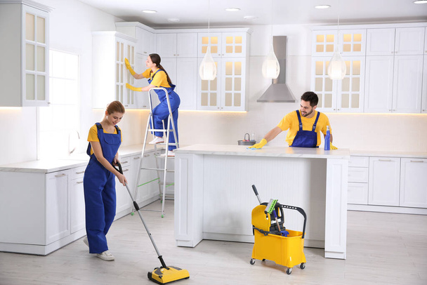 Professzionális takarítók csapata, akik modern konyhát takarítanak - Fotó, kép