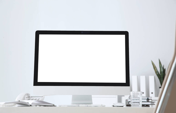 Modern computer with blank screen on table near white wall. Space for design - Photo, Image