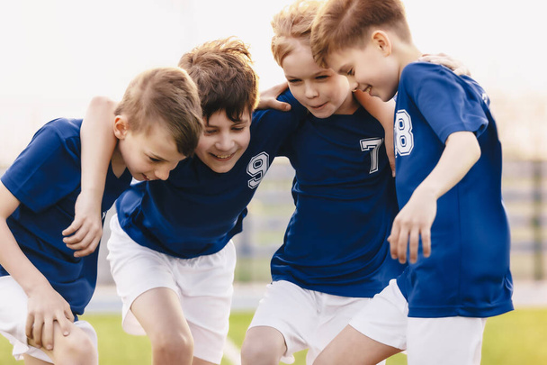 子供サッカーチーム選手。学校のチームで幸せなスポーツ少年。チーム・オン・トーナメント・コンペティションの子供たち。プレイヤーが輪になって集まる。サッカースポーツウェアの子供たち - 写真・画像