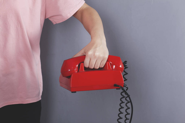woman hand holding red vintage phone on grey  background - Фото, зображення
