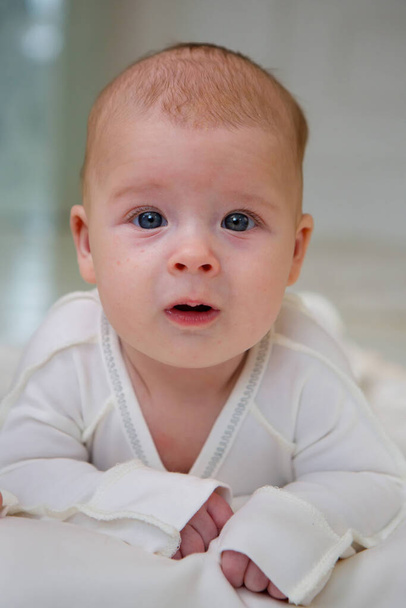 kleine pasgeboren baby jongen liggend in witte kleren op witte deken achtergrond. - Foto, afbeelding