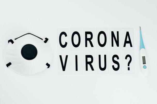 black question inscription corona virus  on white background in the middle  with thermometer and mask from sides - Foto, Imagem