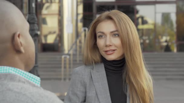 Atractiva joven empresaria hablando con su colega al aire libre - Metraje, vídeo