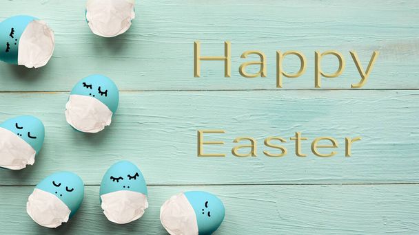 Easter eggs in medical masks and the text Happy Easter on wooden background. Easter quarantine concept - Photo, image
