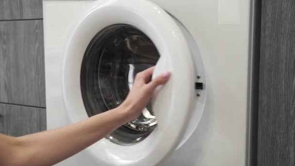 Жіноча рука з одруженим кільцем поклала WHITE CLOTHES в пральну машину. Завантаження пральної машини. Завантажити одяг до пральної машини. Завантажити пральну машинку для білизни. Підготовка прання білизни
 - Кадри, відео