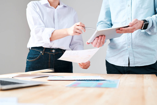 Крупный план неузнаваемого человека, держащего планшет во время обсуждения маркетингового плана с коллегой в офисе
 - Фото, изображение