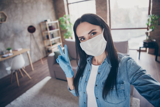 Self-portrait of her she nice attractive lovely brunette girl wearing mask gloves sanitary measures showing v-sign leisure free time healthcare in modern loft brick industrial house apartment - Фото, зображення