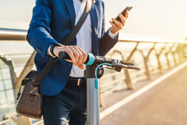 Cropped image of businessman using phone on his electric scooter - Fotoğraf, Görsel
