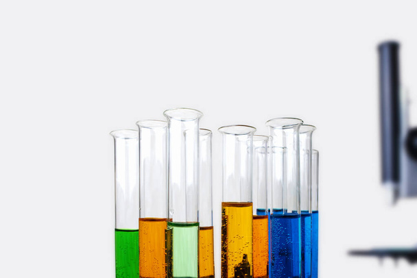 Laboratory test tubes with liquid and blurred metal microscope isolated on light background - Photo, Image