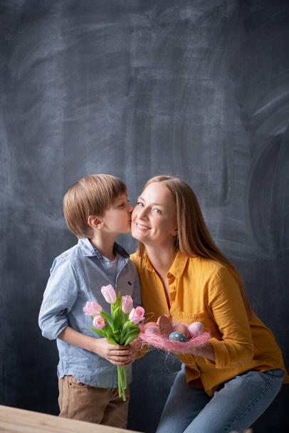 Aranyos fiú csók anyák ellenőrizze, és így tulipán neki, miközben ünnepli vele húsvét - Fotó, kép