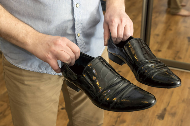 Человек с классической черной лакированной кожей мужской обуви в руках
 - Фото, изображение