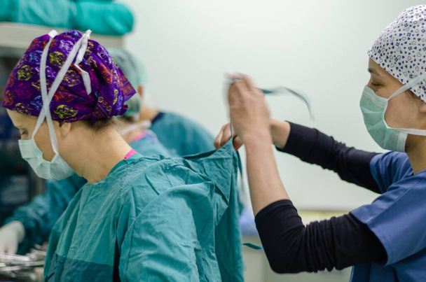 Медсестра или врач носит стерильное хирургическое платье предоперационного
. - Фото, изображение