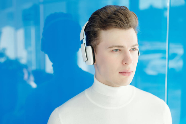 Vážný zamyšlený chlap v moderních bezdrátových sluchátkách hledající do dálky - Fotografie, Obrázek