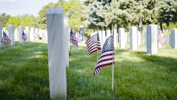 Denver, Colorado, USA-26 maggio 2019 Piccole bandiere americane accanto a lapidi in marmo bianco al cimitero nazionale di Fort Logan il giorno della commemorazione. - Foto, immagini