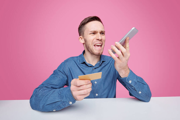 Raivokas nuori miespuolinen asiakas huutaa älypuhelimella samalla valittaen verkkokaupasta toimitettujen tavaroiden laadusta
 - Valokuva, kuva