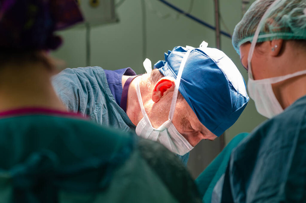 Konzentrierter Arzt und Assistent während einer Hysterektomie-Operation im Krankenhaus. Portrait des Chirurgen. - Foto, Bild