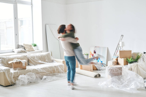 contorno sfocato di giovane uomo vorticoso sua moglie felice nel centro del soggiorno della loro nuova casa o appartamento
 - Foto, immagini