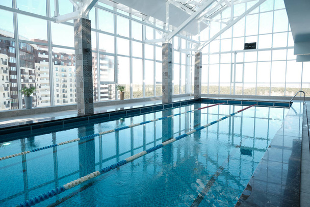 Современный бассейн с чистой водой и разделитель дорожек в фитнес-клуб, спорт и спа-концепция
 - Фото, изображение