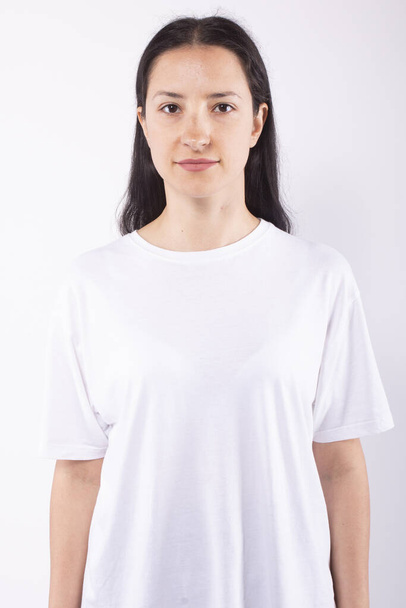 Young woman smiling, standing straight and looking at camera. White background - Fotó, kép