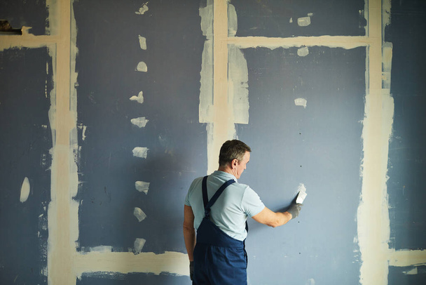 Zadní pohled portrét staršího muže pracujícího na suché zdi při renovaci domu, kopírovací prostor - Fotografie, Obrázek