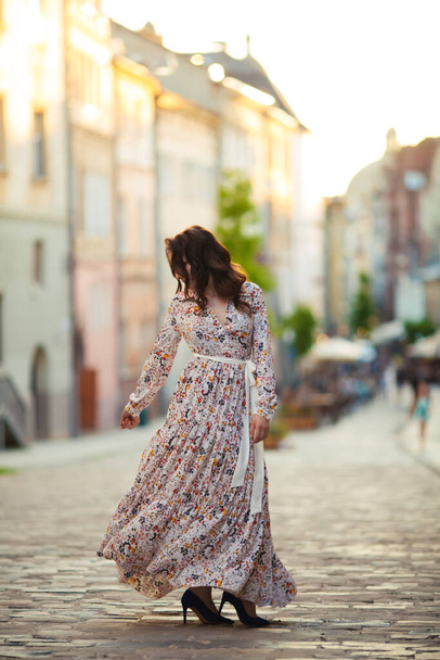 ブルネットは美しい長いドレスでリヴィウの街を歩く. - 写真・画像