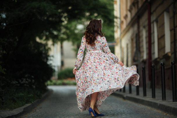 brunette dances on the streets of Lviv in a beautiful long dress. - Фото, зображення